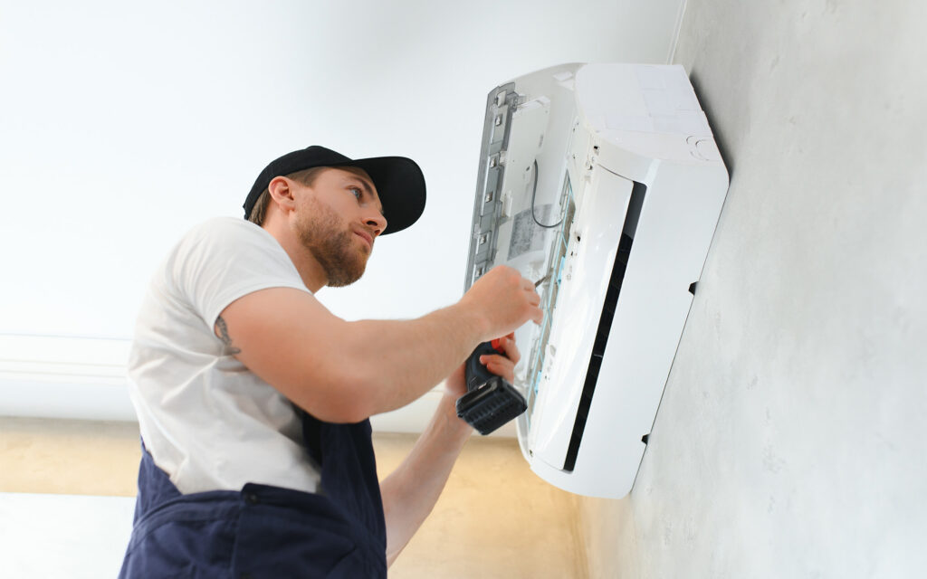 Man with a drill working on interior AC unit