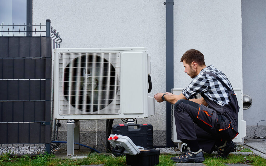 Technician repairing residential hvac unit outside of house