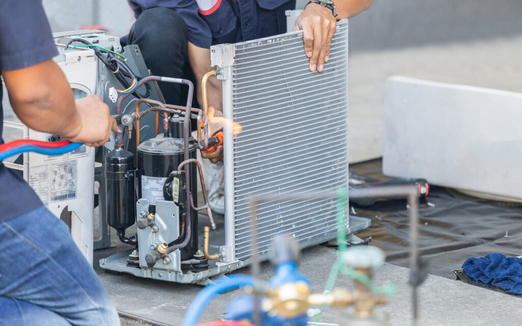 Technicians repairing a commercial HVAC unit