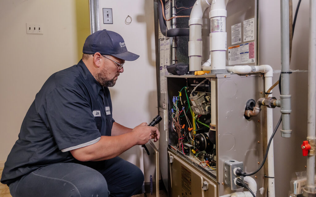 Custom Aire worker looking at HVAC wiring in boiler room
