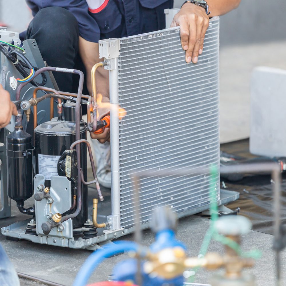 Technicians repairing a commercial HVAC unit